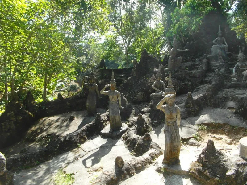 Figuras de piedra desgastadas en un patio de ladera boscosa