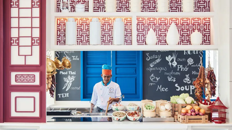 Uno chef a una postazione di cucina thailandese dal vivo nell'Amaya Food Gallery dell'Amari Koh Samui