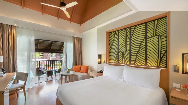 Una camera deluxe con vista piscina all'Amari Koh Samui, con testiera a motivo di foglie, letti singoli e un balcone