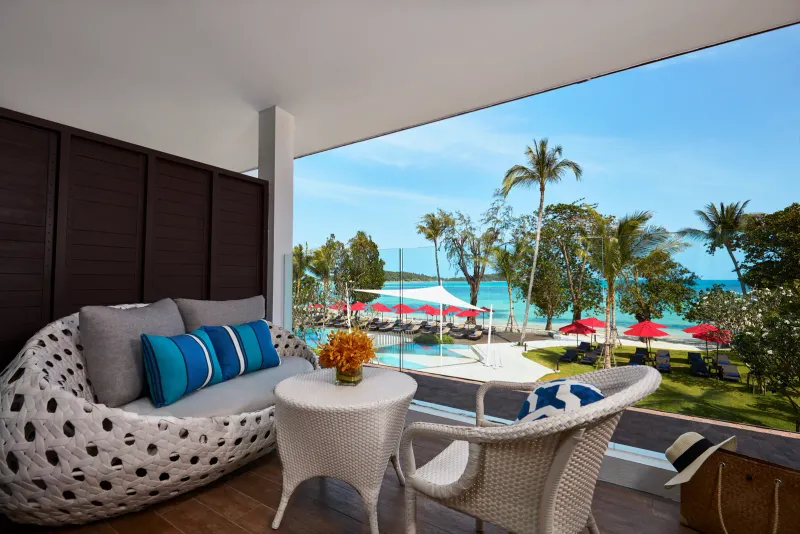 La terrazza di una camera dell'Amari Koh Samui con una poltrona di vimini che guarda la piscina verso la spiaggia di Chaweng