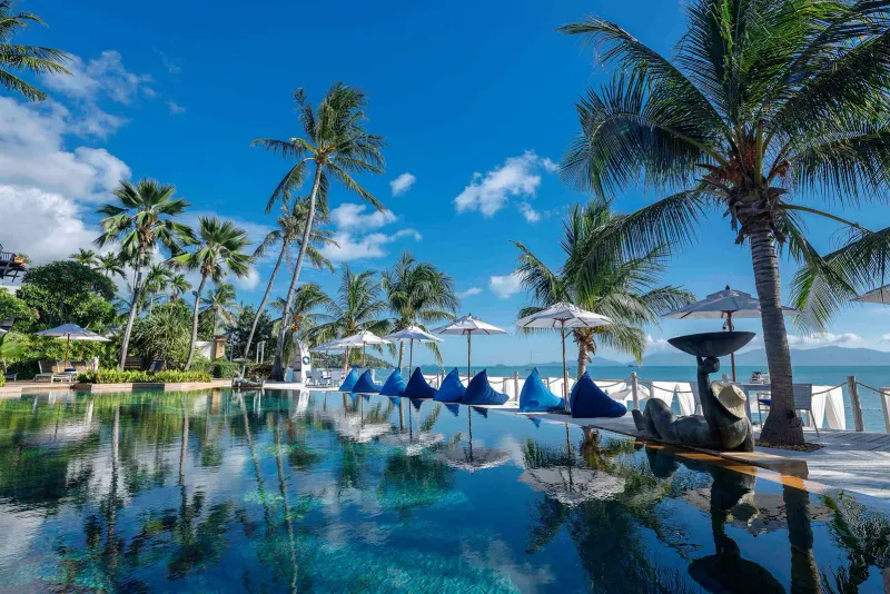 ヤシ、パラソル、ビーンバッグが並び、海に面した、Anantara Bophut Koh Samuiのビーチフロントのインフィニティプール