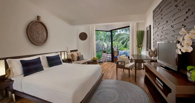 広いベッド、濃い色の木の家具、庭の眺めがある、明るいAnantara Bophut Koh Samuiのスイート