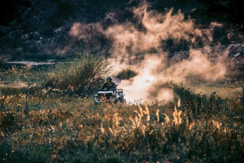A quad bike kicking up dust trails on a grassy field in Thailand