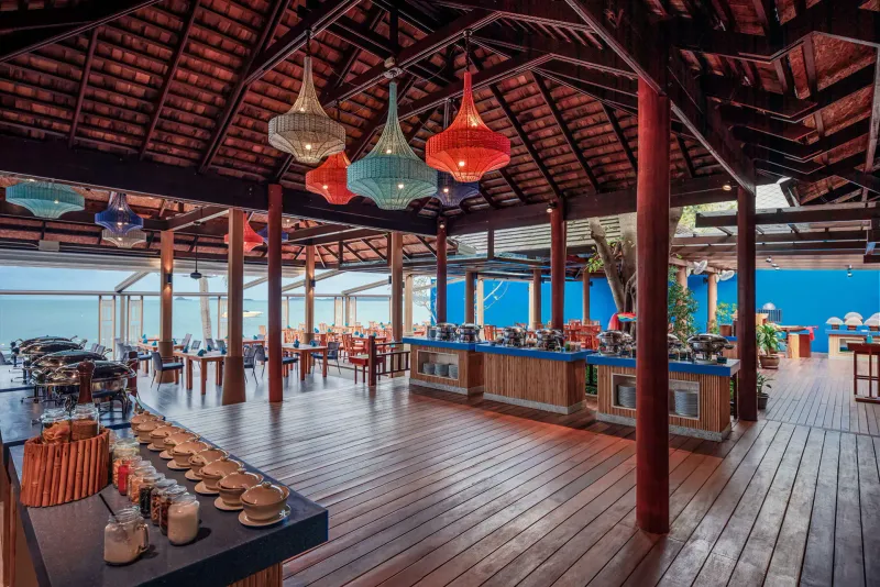 Sala del buffet a lati aperti al Bandara Resort Samui con lampade di vimini e vista mare