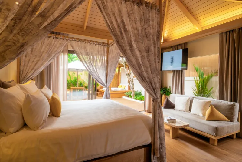 Letto a baldacchino e divano in una villa con piscina del Bandara Resort Samui con una terrazza sul giardino dietro