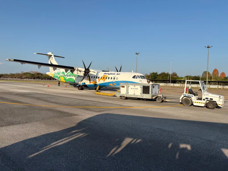 Turbopropulseur ATR de Bangkok Airways aux couleurs vives, stationné sur le tarmac d'un aéroport avec un groupe de parc électrique au sol