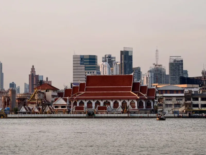 Bangkok skyline with Wat Yannawa temple beside the Chao Phraya River at sunset