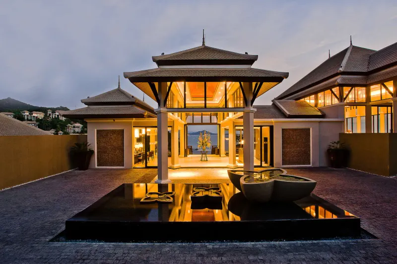 Veduta al crepuscolo del padiglione d'ingresso di una villa del Banyan Tree Samui con una fontana di loti e il mare dietro
