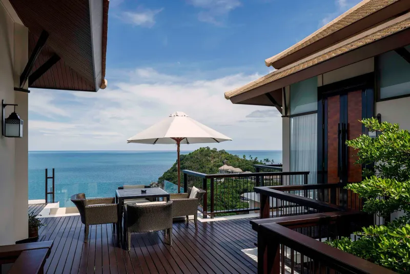 Terrazza di una villa del Banyan Tree Samui con sedie di vimini, un parasole e una lunga vista sul Golfo di Thailandia