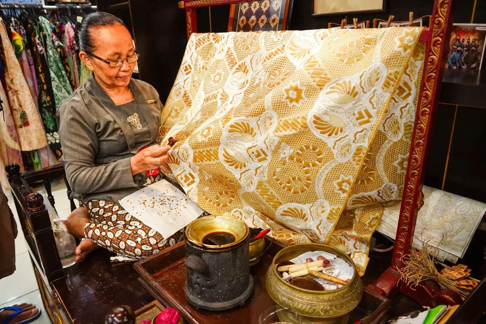 A craftswoman applies hot wax to fabric with a traditional tool as part of the batik dyeing process