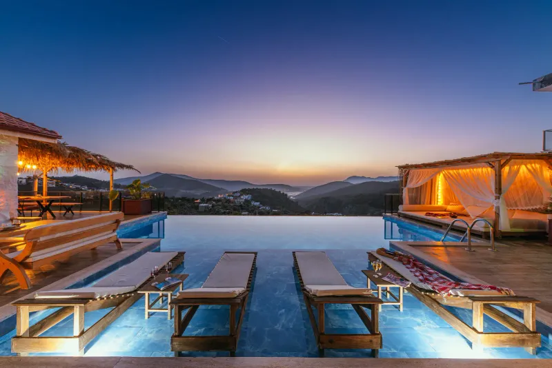 A resort infinity pool with sun loungers and hillside views