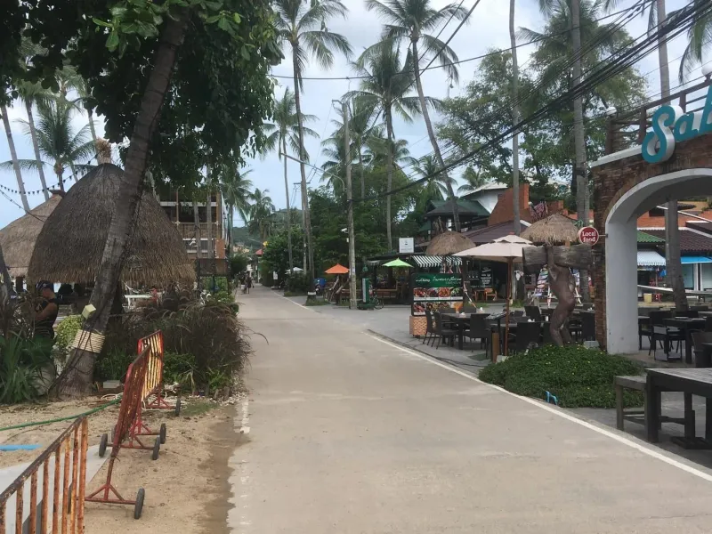 Fisherman's Village walking street in Bophut, Koh Samui, lined with thatched-roof restaurants near the boat charter office