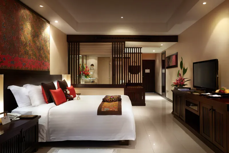 Camera deluxe del Bo Phut Resort and Spa con letto king, cuscini di seta rossa e mobili thailandesi in legno scuro
