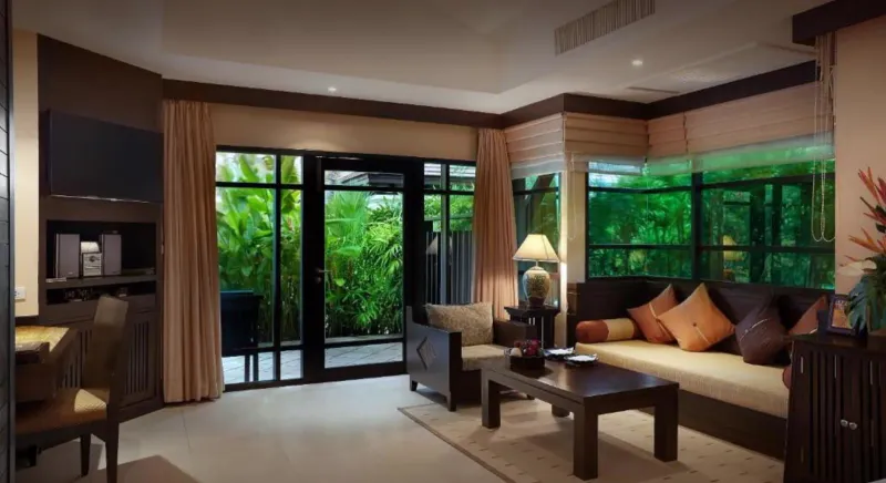 Zona giorno di una villa del Bo Phut Resort and Spa con divani, cuscini e porte scorrevoli di vetro sul giardino