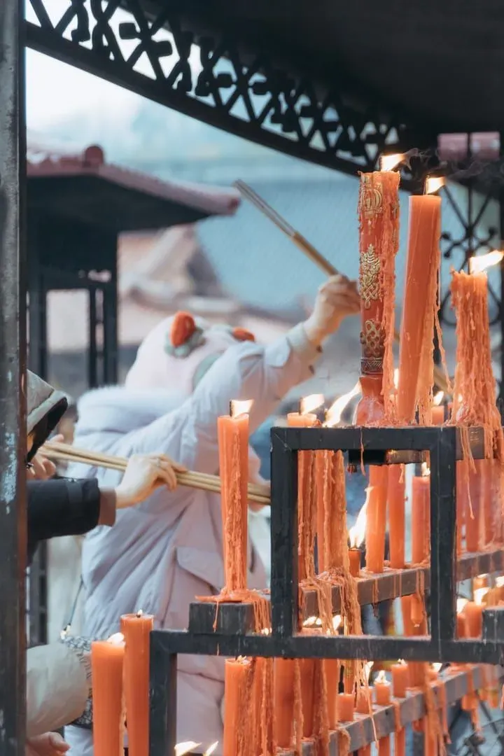 Visitors lighting candles at a Thai Buddhist temple altar on a holy day