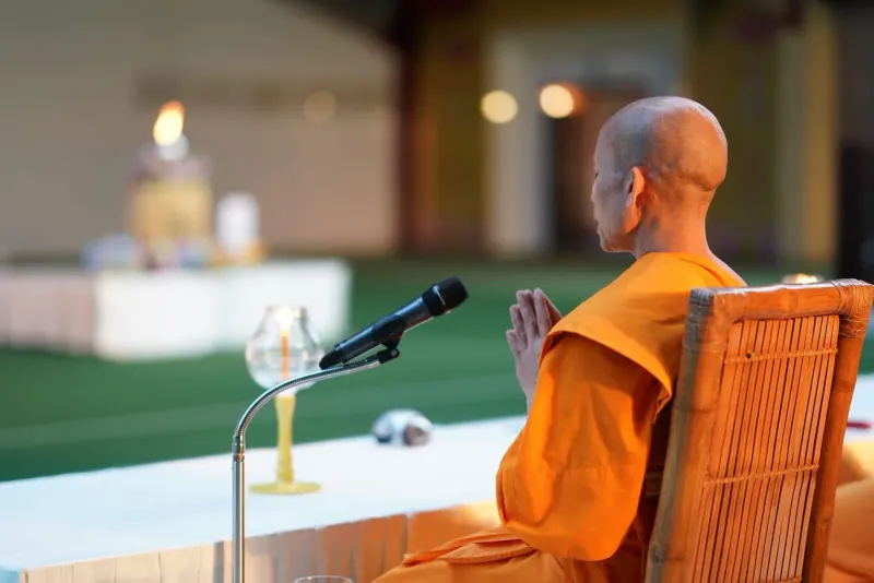 Buddhist monk in saffron robes seated in a temple hall during a Koh Samui holy day ceremony