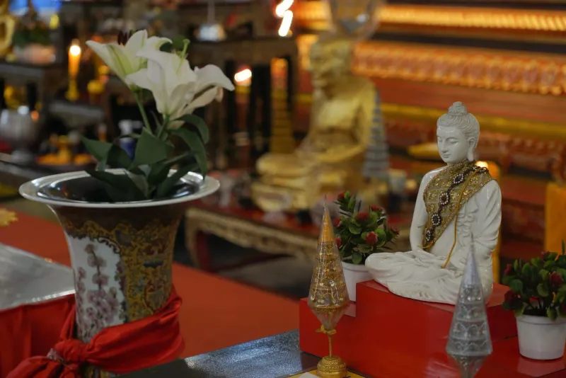 Ornate Buddhist altar with statue, flowers and candles arranged for a holiday offering