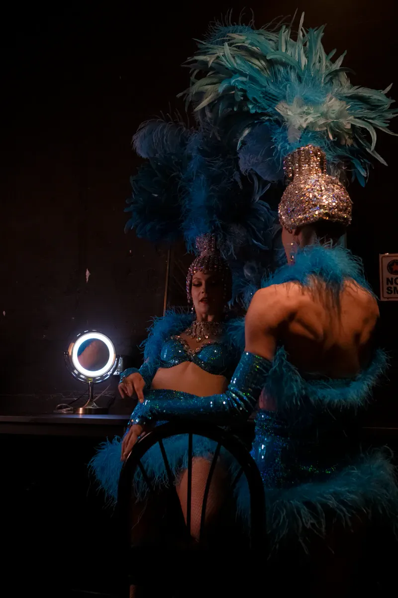 Showgirls in feathered costumes preparing backstage for a cabaret performance