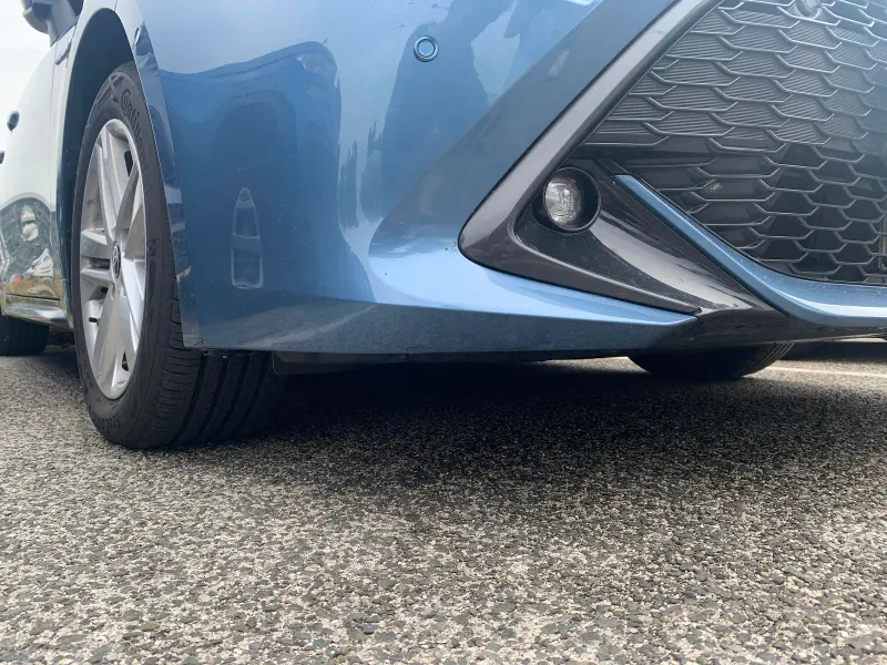 地面の高さから撮った、青い車の前バンパーとホイールアーチのアップ