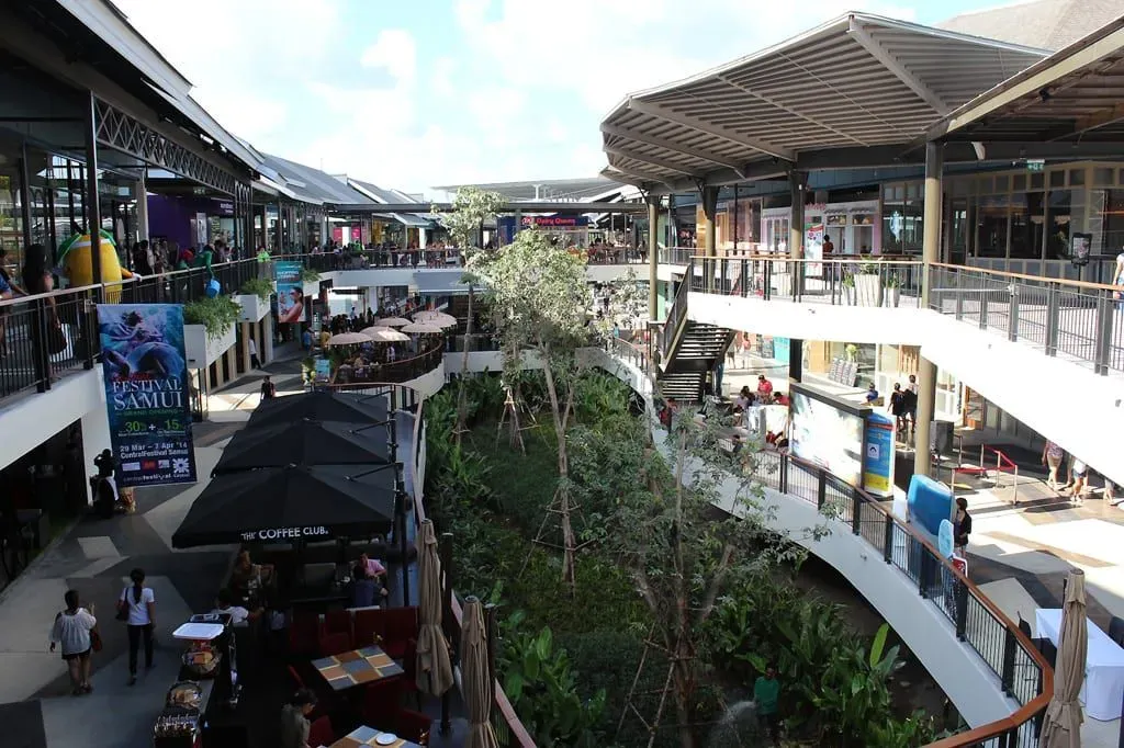 Central Samui shopping mall interior courtyard with escalators, terrace dining and landscaped greenery
