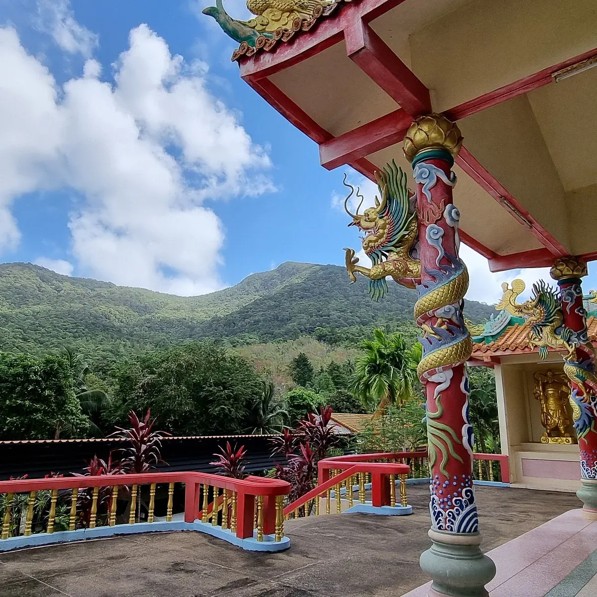 Goldene, drachenverzierte Säule auf einer Terrasse mit Blick auf grüne Hügel beim Guam Im Schrein