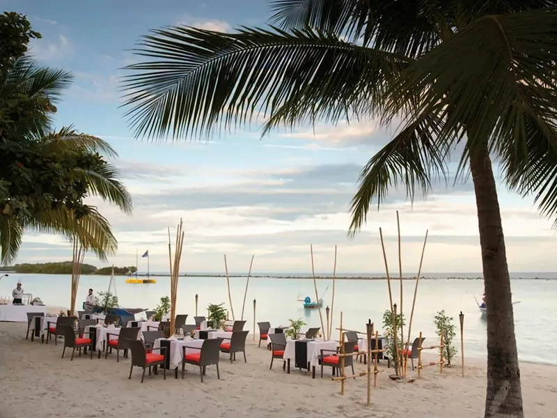 Tables dressées pour le dîner sur le sable au coucher du soleil, avec torches et palmiers, Chaweng Regent Beach Resort