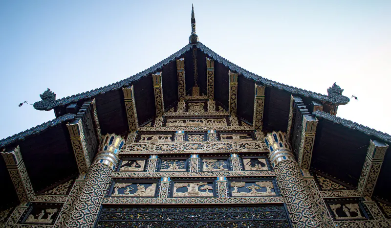 晴れた空の下の、チェンマイにある北タイの寺院の、彫刻を施した木の破風