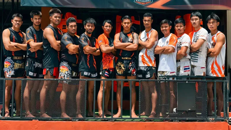 Chor Ratchawat fighters and trainers standing in a row on the gym balcony in team shirts