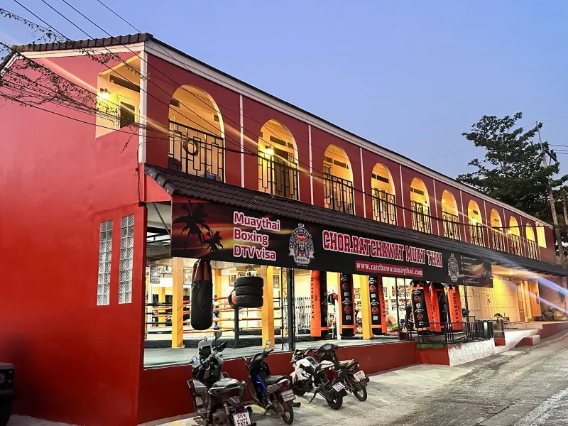 The red two-storey front of a Chor Ratchawat Muay Thai camp with the gym signboard along the upper floor