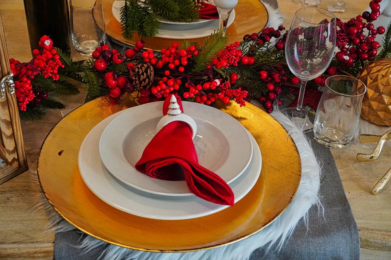 Christmas place setting with a red napkin on a gold plate