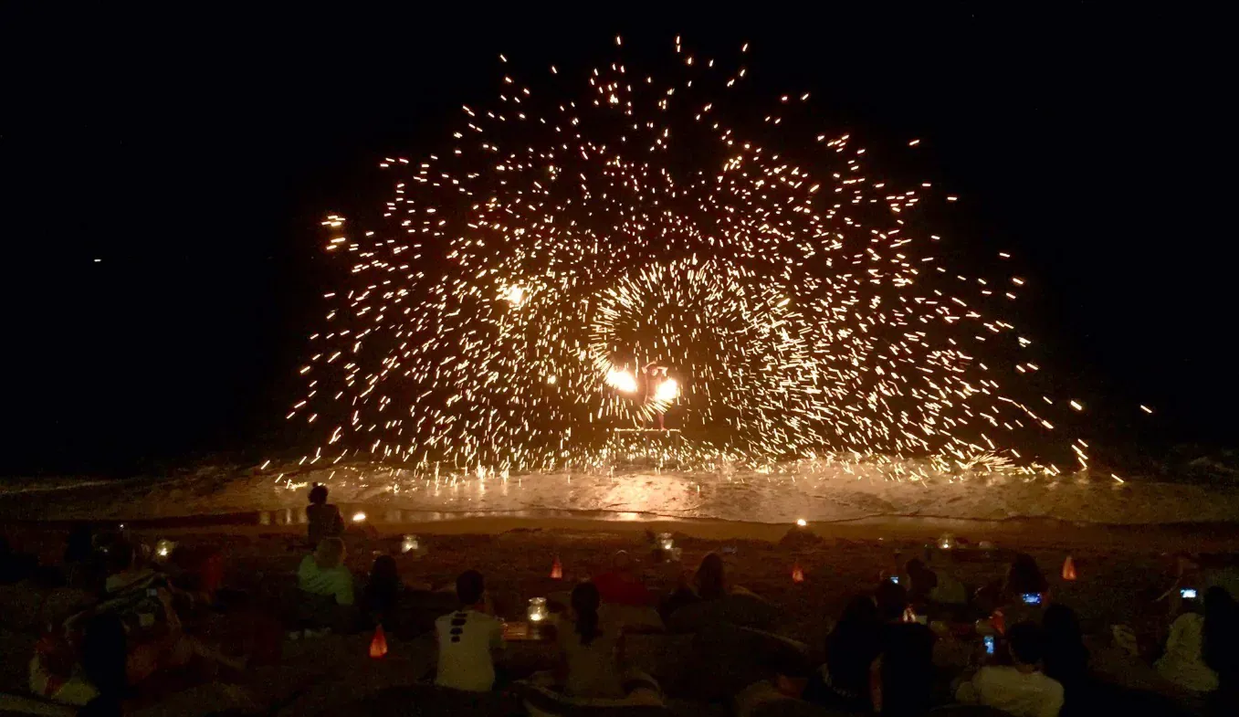 A fire dancer performing on the beach at Coco Tam's, sparks fanning out across the night sky