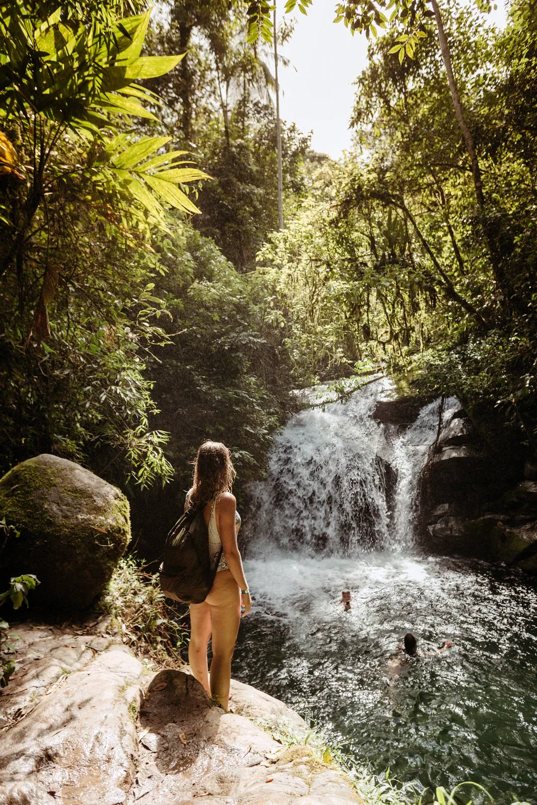 Un excursionista se refresca en una poza de cascada a la sombra de la jungla, como la que se encuentra al pie de las cascadas de Tan Rua