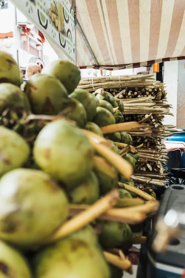 Fresh coconuts and sugarcane stacked at a Thai roadside market stall near Koh Samui