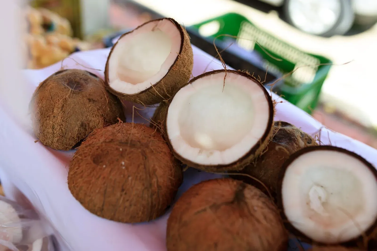Fresh coconuts split open in half and displayed on a market table showing the white flesh inside