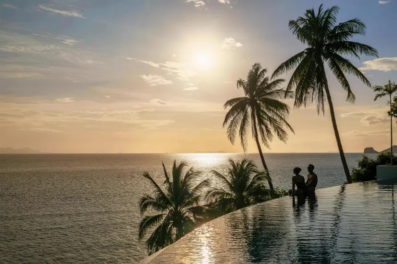 Sunset infinity pool at Conrad Koh Samui with palm trees and Five Islands silhouette, Taling Ngam