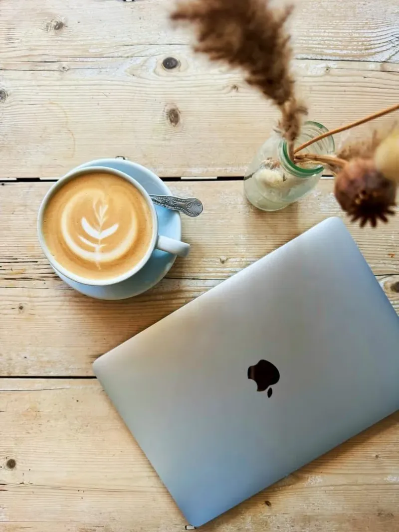 Latte and laptop on a wooden café table, part of the Koh Samui remote work routine