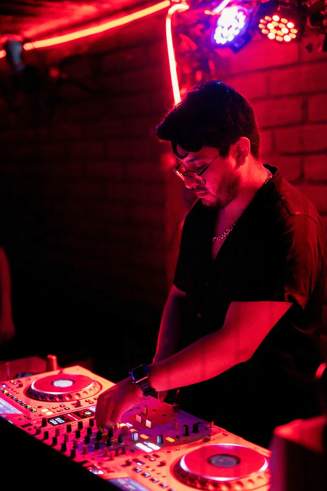 DJ in red light at the decks of a night club