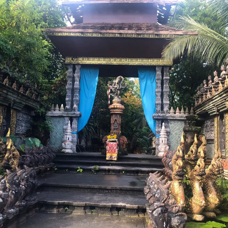 The blue-draped shrine gate at Dusit Dhewa, flanked by carved stone pillars and a Ganesh statue