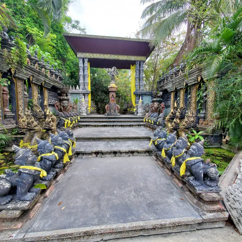 The yellow-draped naga-flanked shrine pavilion at Dusit Dhewa, seen from the stone walkway