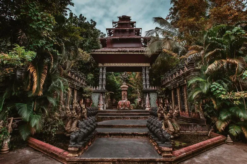 The pagoda-roofed shrine pavilion at Dusit Dhewa framed by tropical palms and naga guardians