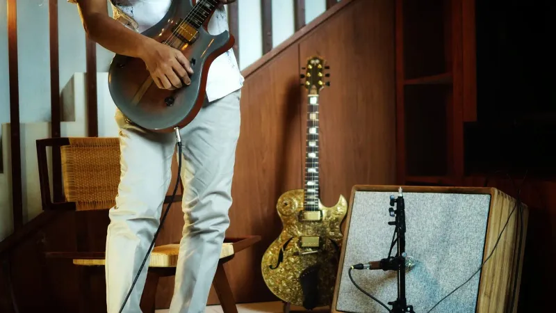 Guitarist playing electric guitar beside an amplifier
