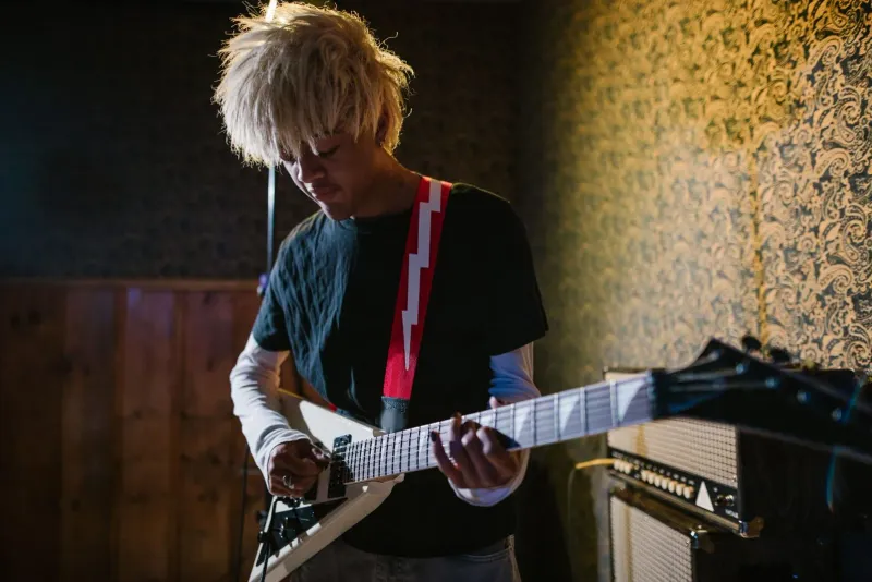 Musician playing an electric guitar in a cozy indoor rehearsal setting