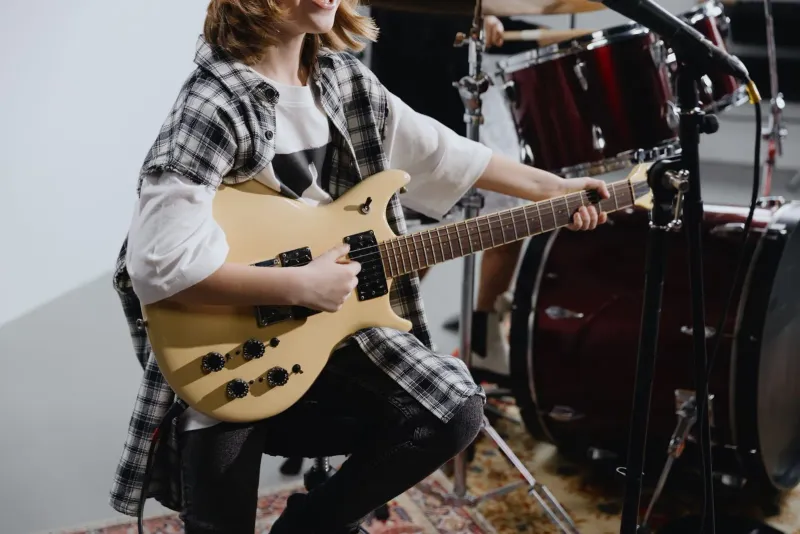 Jeune musicien jouant d'une guitare électrique, le profil d'interprète en âge scolaire qui répète dans une salle de musique communautaire