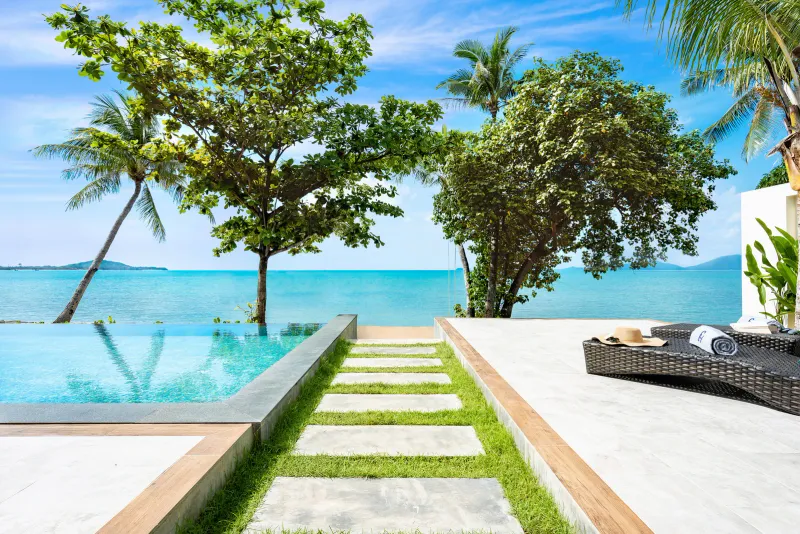 Piscine à débordement d'une villa et chemin de pierres vers la mer à Fair House Villas & Spa