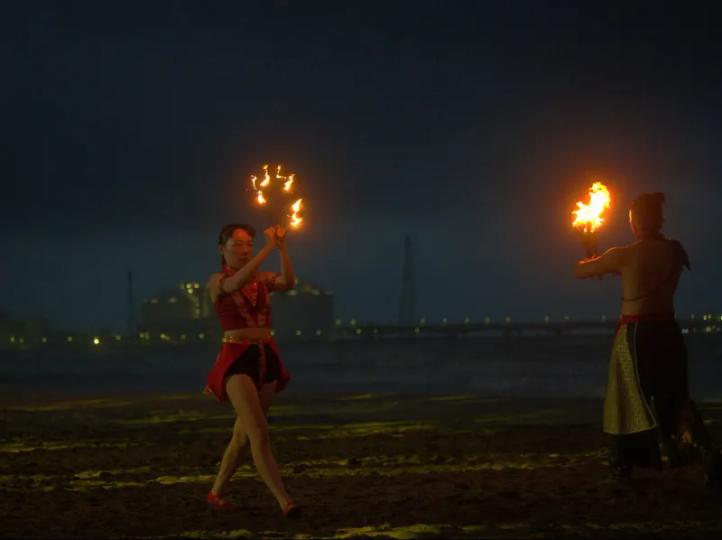 Two fire dancers performing on a beach at night