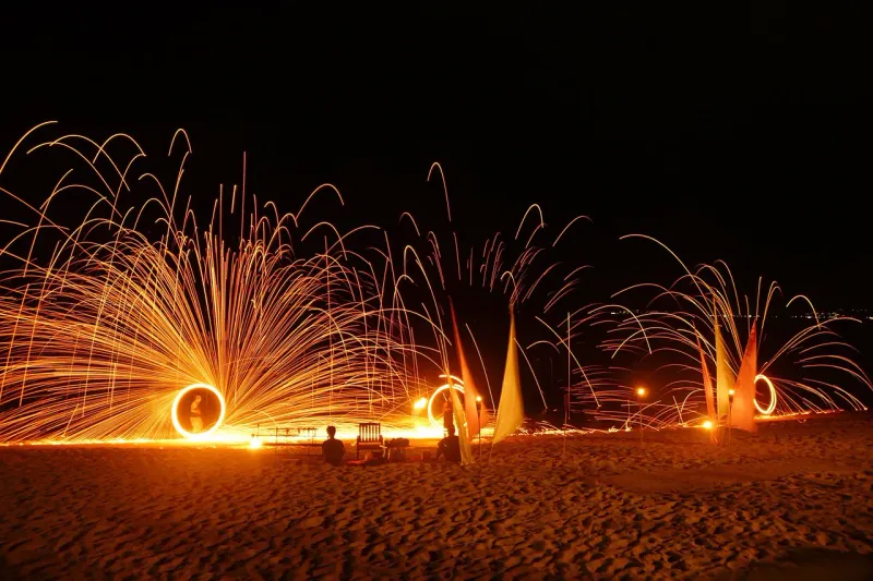 Eine Feuershow mit Stahlwolle an einem Strand in Thailand bei Nacht