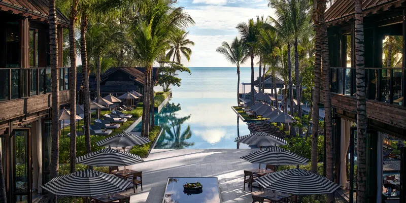 Infinity pool and palm-lined terrace at Kimpton Kitalay Samui, Choeng Mon Beach, close to FishHouse Restaurant's beachfront setting
