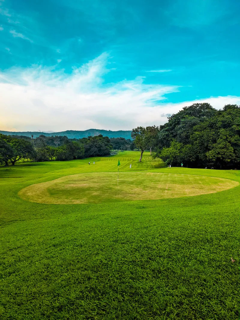 A scenic golf course with lush green grass under a blue sky in Thailand