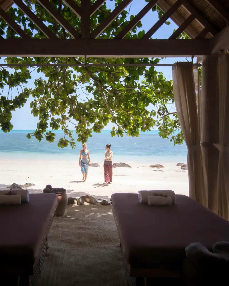 Pavillon de spa face à la plage avec deux tables de massage sous un toit en bois au Four Seasons Resort Koh Samui