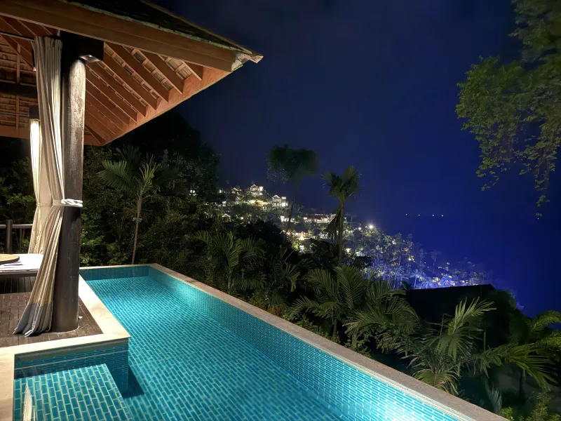 Piscine à plonger d'une villa au coucher du soleil, avec terrasse et lumières lointaines de la côte sous le Four Seasons Resort Koh Samui